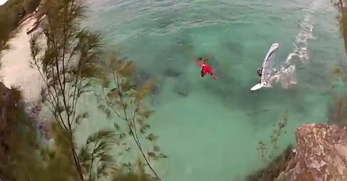 VIDEO Un barbat care sare de pe o stanca evita la limita ciocnirea cu un practicant de windsurfing